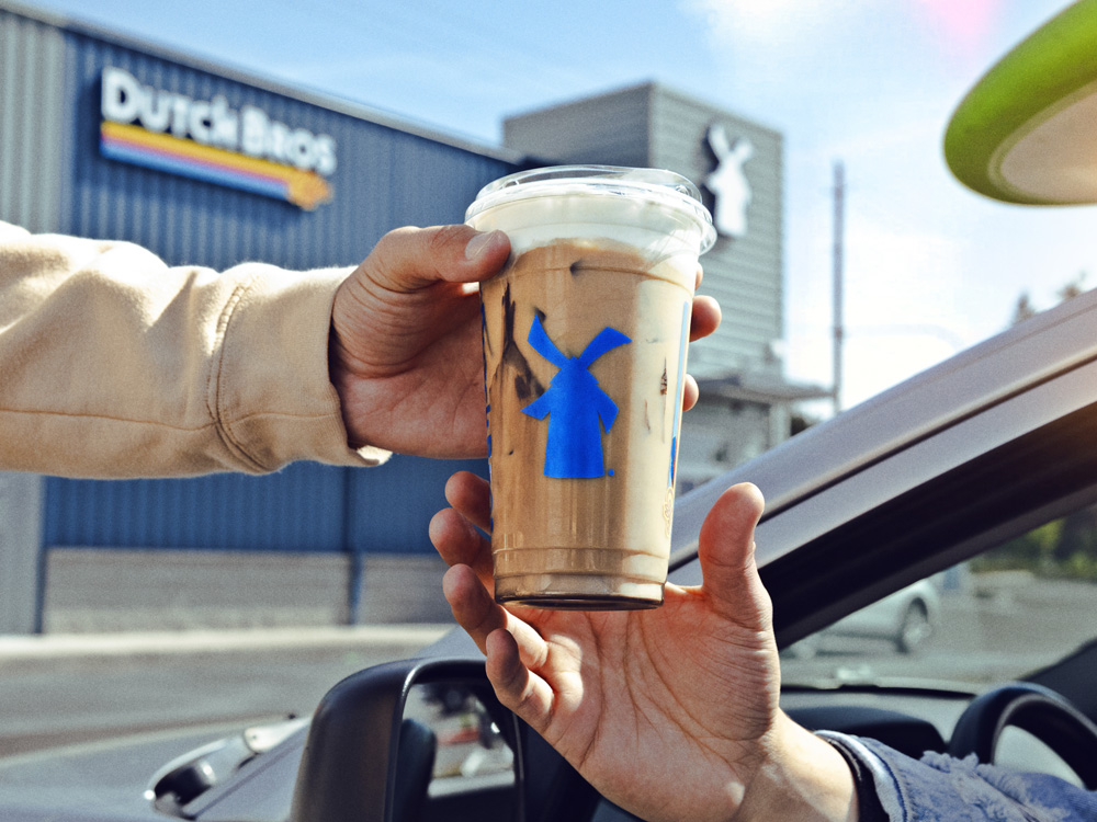 Driving through where person hands off coffee order to the person in a car