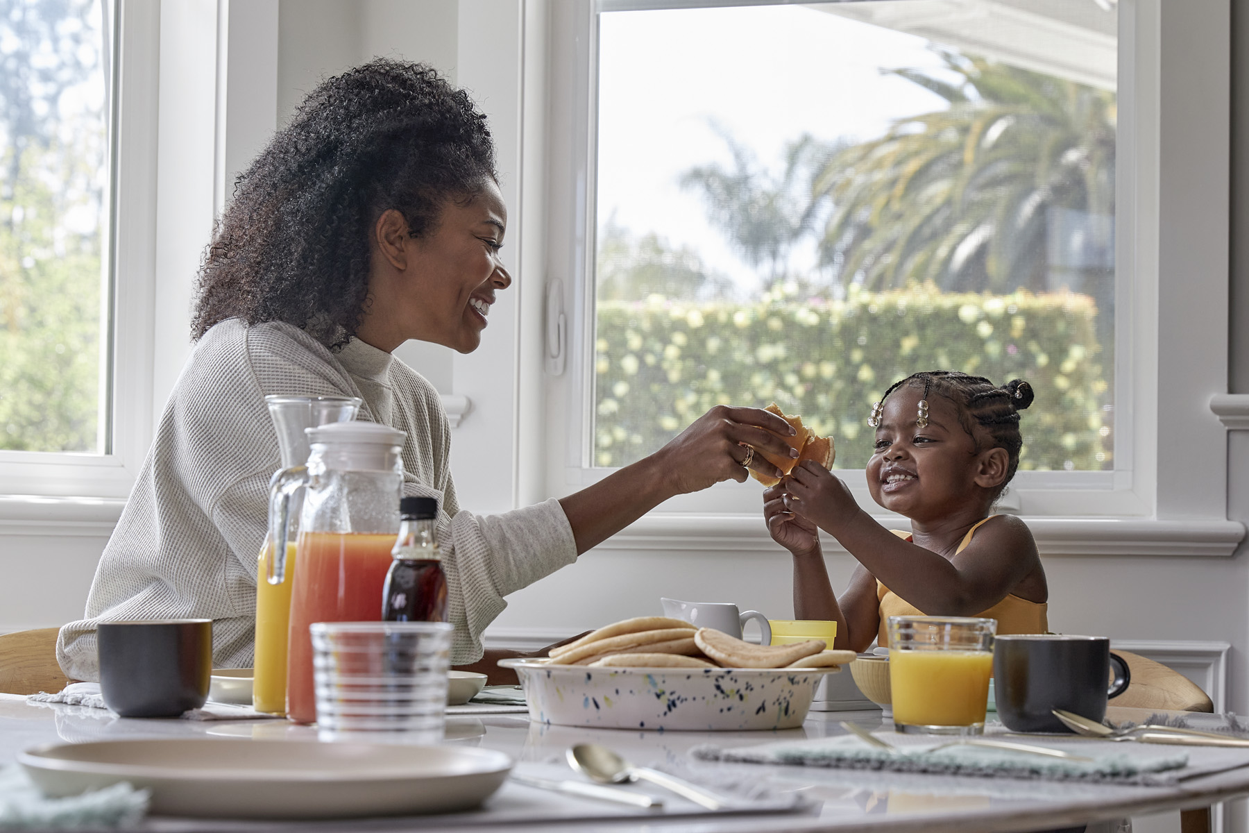 Mother feeding young daughter at a table.