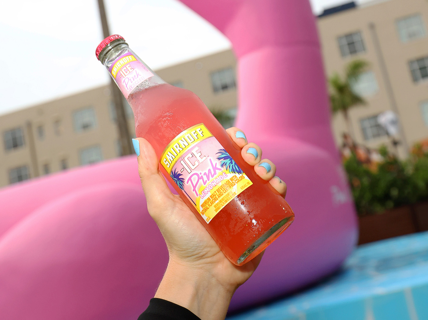 Pink Flamingo sits in background and a hand holding Smirnoff lemonade