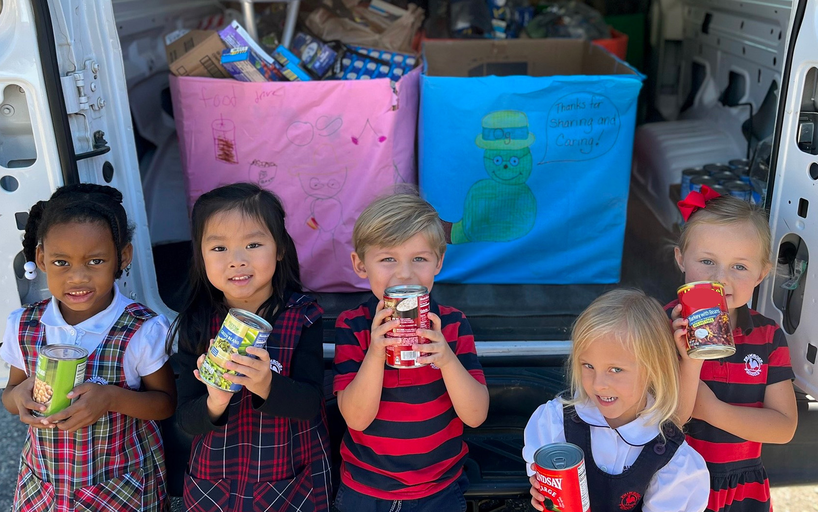 Students at Primrose School of Fleming Island (Fleming Island, FL) help to prepare donated canned goods for delivery.