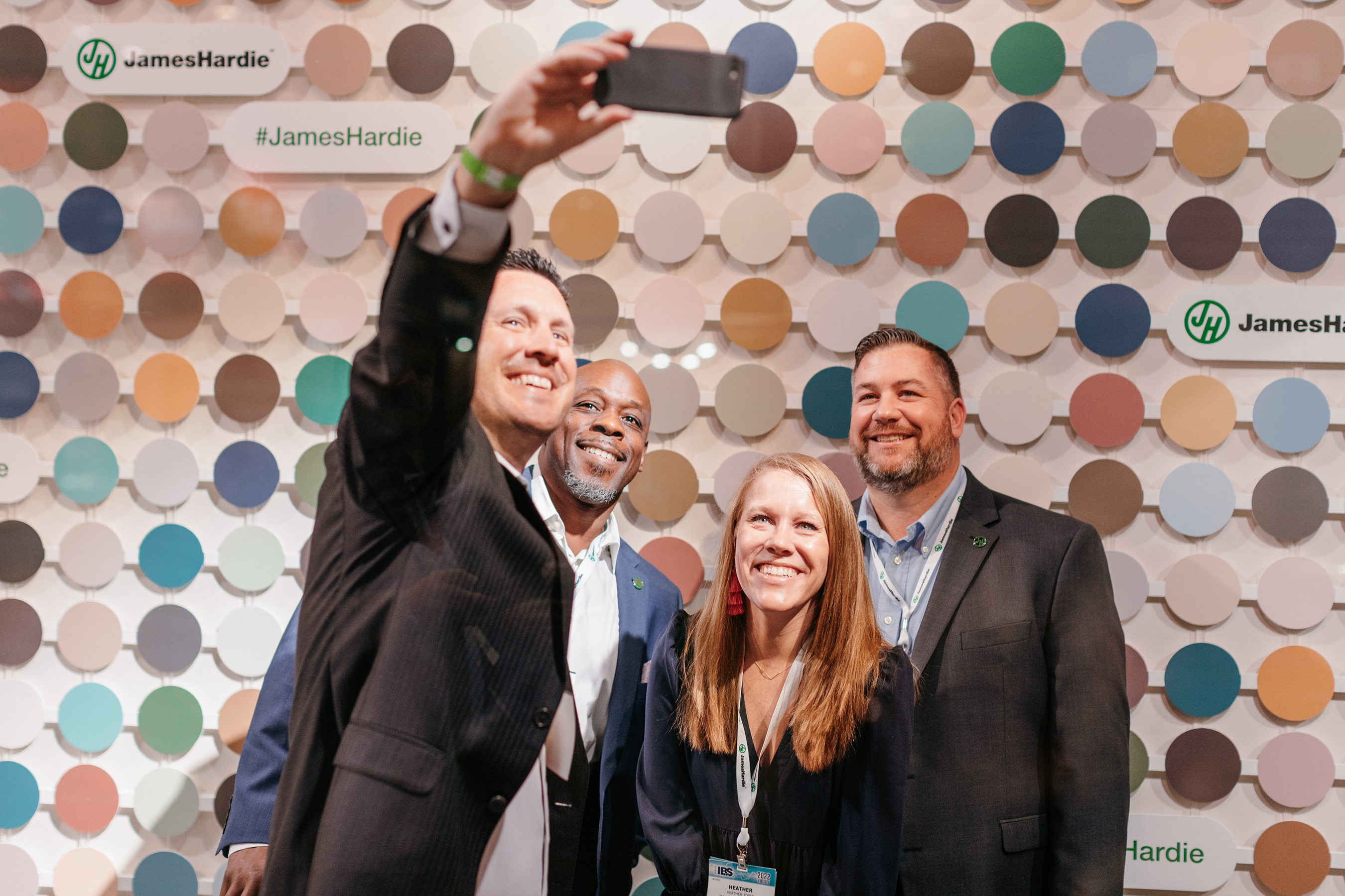 James Hardie employees take a photo in front of ColorPlus® Technology wall (from left to right: Greg King, Director, Sales Midwest; Preston Hills, Regional Account Manager; Heather Jones, Senior Manager, Retail Marketing; Hans Uslar, Distribution Demand Leader, Midwest).