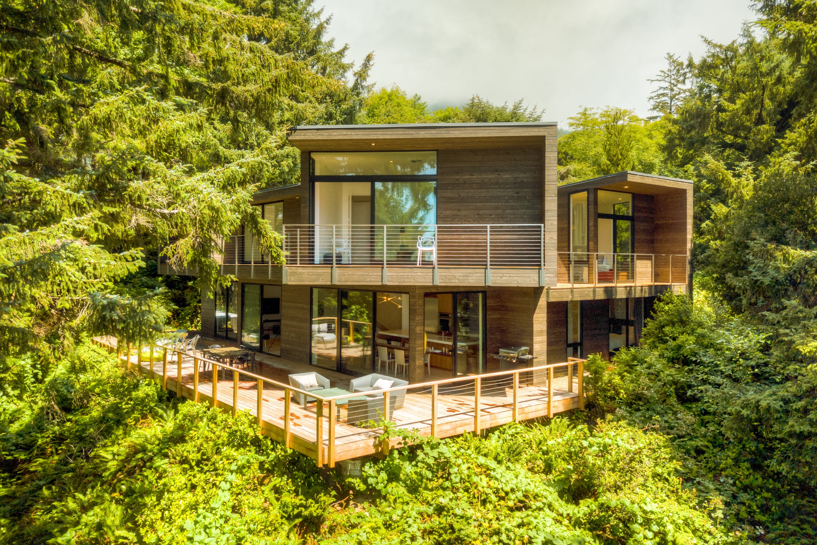 Manzanita, Oregon – A modern architectural masterpiece nestled in trees. Floor-to-ceiling windows bathe the space in light with views of Neahkahnie Beach.
