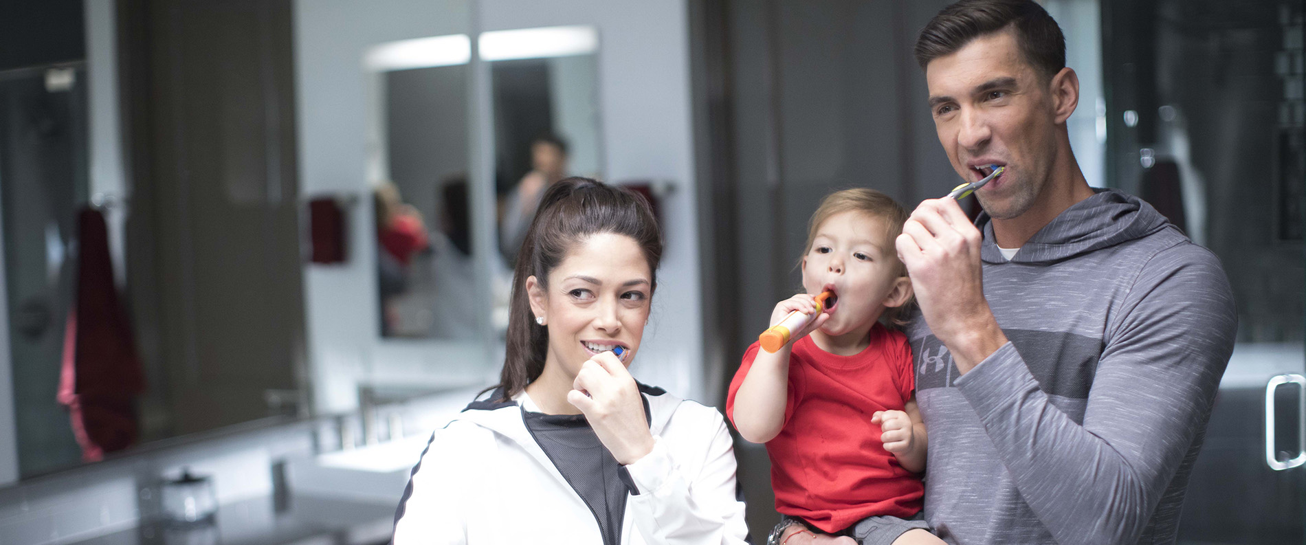 Michael Phelps and his family are brushing their teeth in the bathroom with Colgate toothpaste.