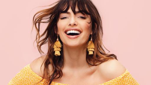 Magazine cover of a woman in yellow dress laughing.