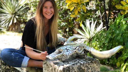 Sabrina Yanguas sitting by a painted cow skull