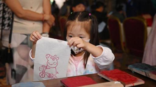 Child showing a drawing of a pig on a bicycle