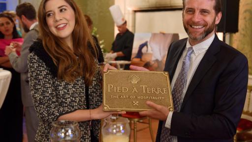 Mujer y hombre sosteniendo una placa de recompensa Pied a Terre.