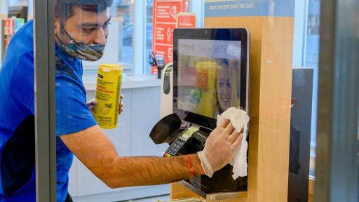 Shoppers Drug Mart employee sanitizes self checkouts