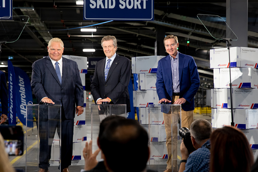 Doug Ford, premier ministre de l'Ontario, John Tory, maire de Toronto, John Ferguson, président et chef de la direction de Purolator, activent les quatre kilomètres de convoyeurs au centre de tri national de Purolator, le tout nouvel établissement de tri à la fine pointe de la technologie de l'entreprise.