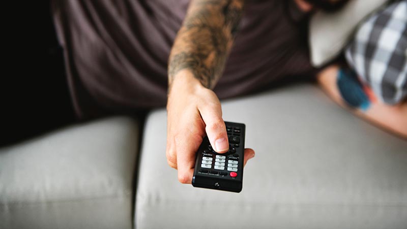 Person on couch changing the channel with a remote control