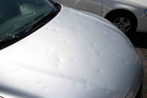 Hail damage to windshield and hood of car