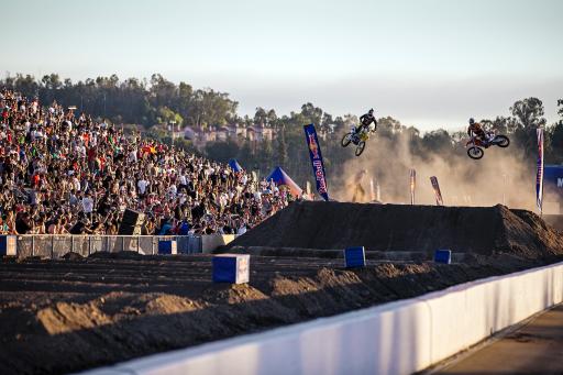 Riders go airborne as they hit the jump side-by-side during close racing action  