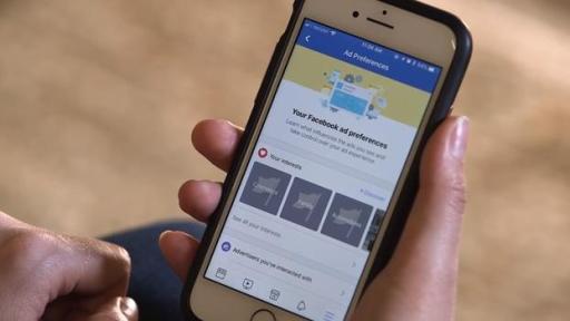 Woman scrolling through her mobile phone on Facebook to reveal Facebook Ad settings