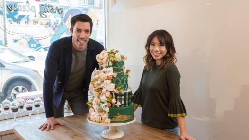 Drew Scott and Linda Phan show off a green and decorative wedding cake.