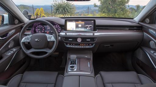 2019 KIA K900 interior design view of steering wheel, seats, dashboard panel, and rear view mirror as well as a shot of nature, some trees, in looking beyond the front window.