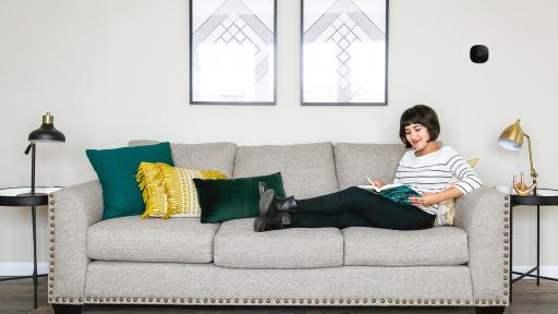 Woman lounging on grey couch, ecobee thermostat on the wall nearby