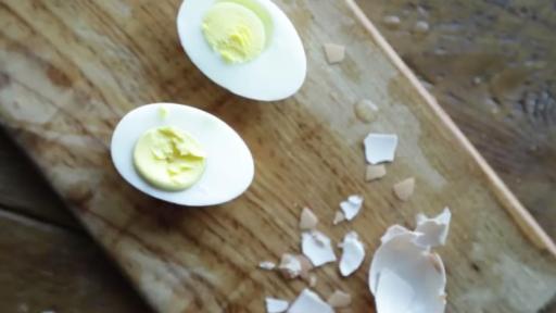Peeled hard-boiled eggs lying beside their cracked shells.