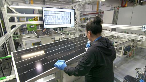 A woman testing solar cells in a factory.