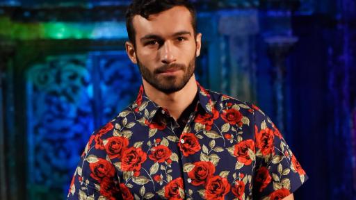 Male model posing wearing a floral short sleeve cotton button-up with black pants