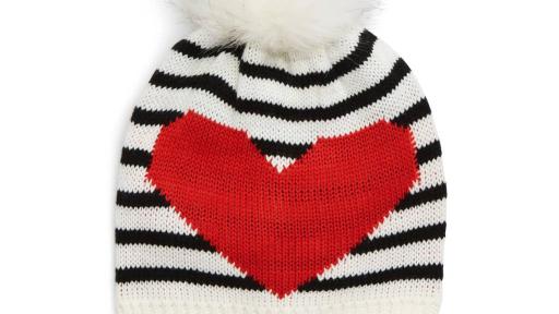 White beanie with black stripes and a furry pom at the top.