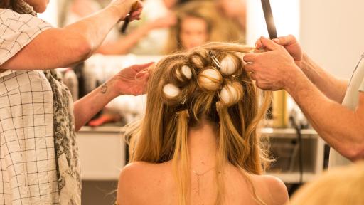 The back of a blond model's head with hair in curlers.