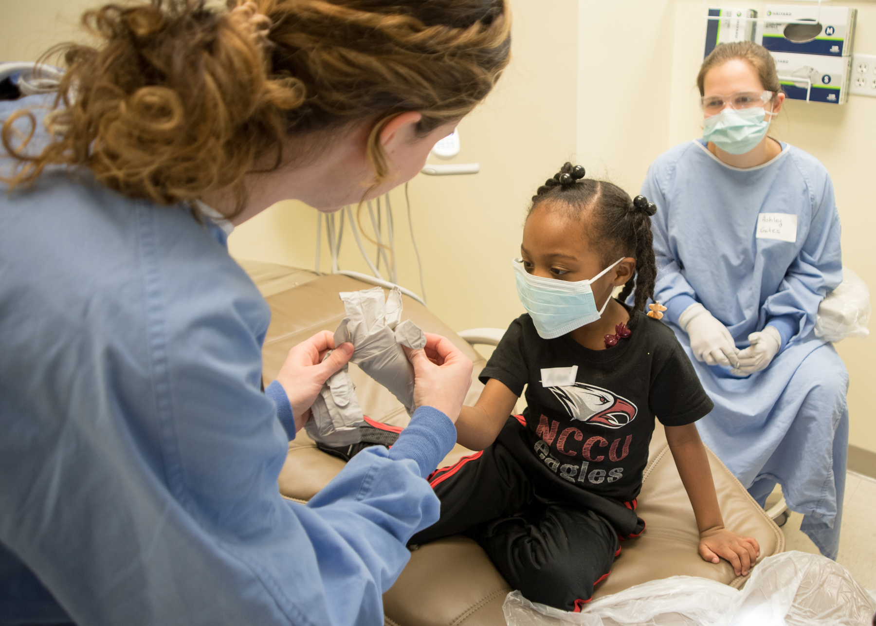 UNC-CH School of Dentistry personnel make the dentist's office a more fun place by allowing the children to try on gloves and masks in the dental chair.