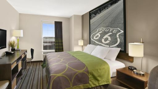 A nice hotel room with a king-sized bed, overlooked by a large Route 66 picture hung on the wall.