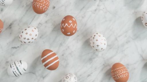Various brown and white eggs with simple geometric designs made with paint pens.