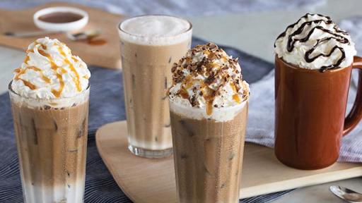four coffee drinks some with whip cream, chocolate and caramel toppings