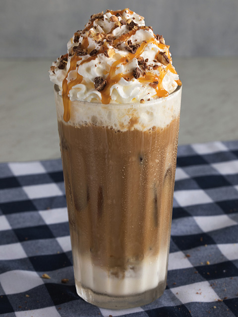Iced Goo Goo Cluster Latte in glass cup with whip cream, chocolate and caramel toppings