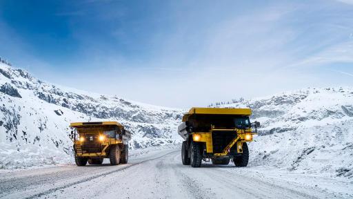 Two large trucks driving in the snow