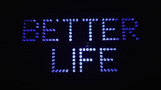 "Better Life" written in purple lights on a black backdrop.