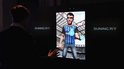 Man interacting with an avatar on a screen. The avatar is in a soccer stadium full of people and is wearing a soccer jersey.