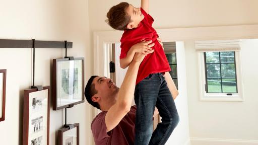 A man holds his son up to an alarm to test fire alarms.
