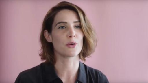Close-up of Cobie Smulders on a pink background as she speaks on Bullying for a YouTube video.