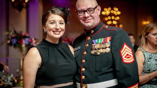 A highly decorated military member in full uniform standing with his wife for a photo.