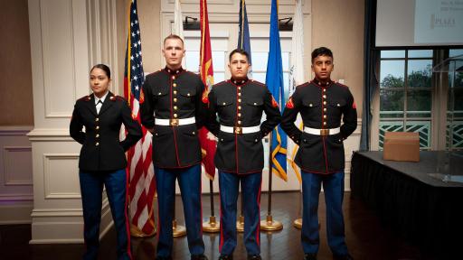 Four National Guard service members standing in front of flags in full uniform.