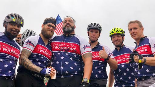 Men standing with their wearing biking jerseys with stars on the shirts.