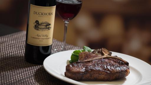 A steak beside a wine bottle.