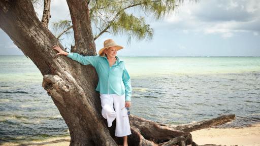 Martha Stewart leaning against a tree on the beach