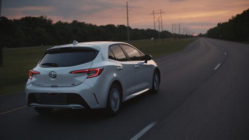 A silver 2019 Toyota Corolla Hatchback driving on a long road.