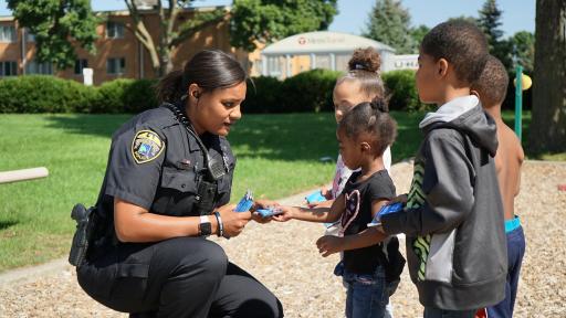 Female cop handing out Hershey's bars to children in neighborhood