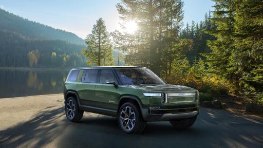 A green SUV on a parking lot surrounded by pine trees.