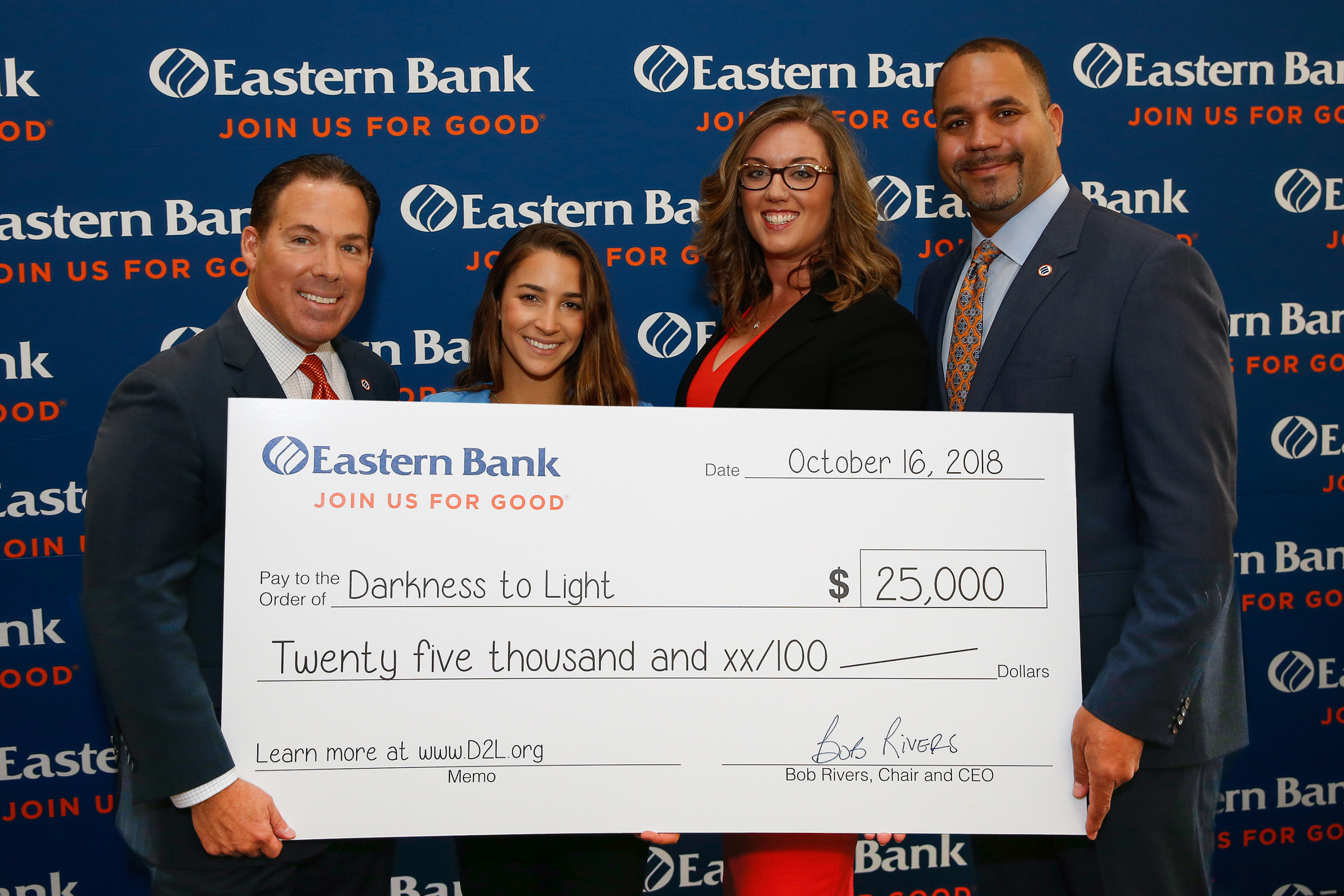 Bob Rivers (left), Chair & CEO of Eastern Bank, and Quincy Miller (right), Vice Chair & President of Eastern Bank, present Aly Raisman and Katelyn Brewer with a donation for $25,000 to Darkness to Light.
