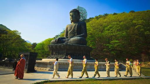Meditators walking around a giant outdoor statue of the Buddha