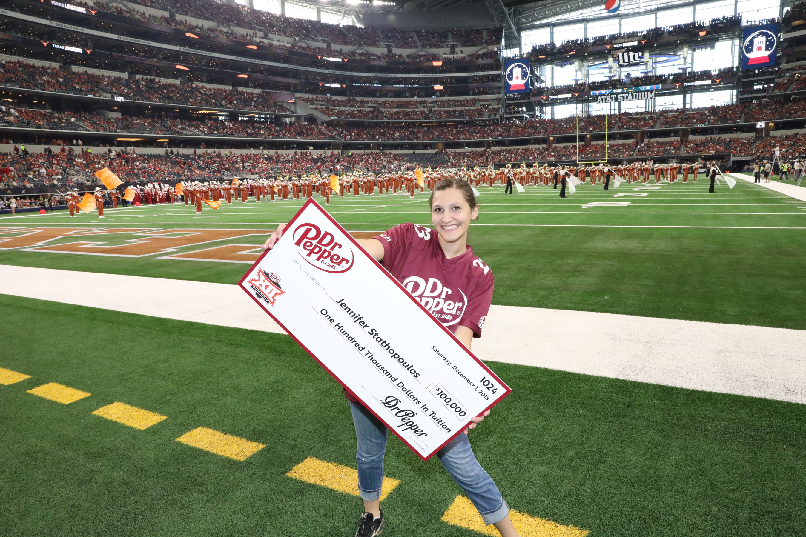 Jennifer Stathopoulos poses with her check for $100,000 in tuition after winning the Dr Pepper Tuition Giveaway during halftime of the Big12 Conference Championship