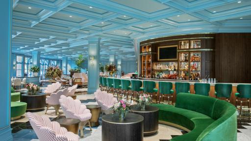 Sadelle’s Interior highlighting the bar and old european style with velvet green chairs and couches and a teal ceiling.