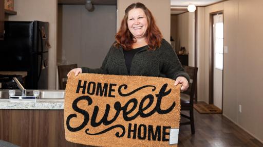 Woman holds up a home sweet home doormat