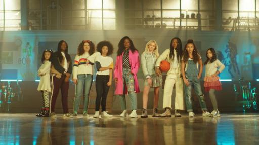 Girls standing in a gymnasium with basketballs.