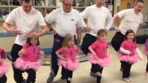 Dads dancing with their young daughters wearing tutus.
